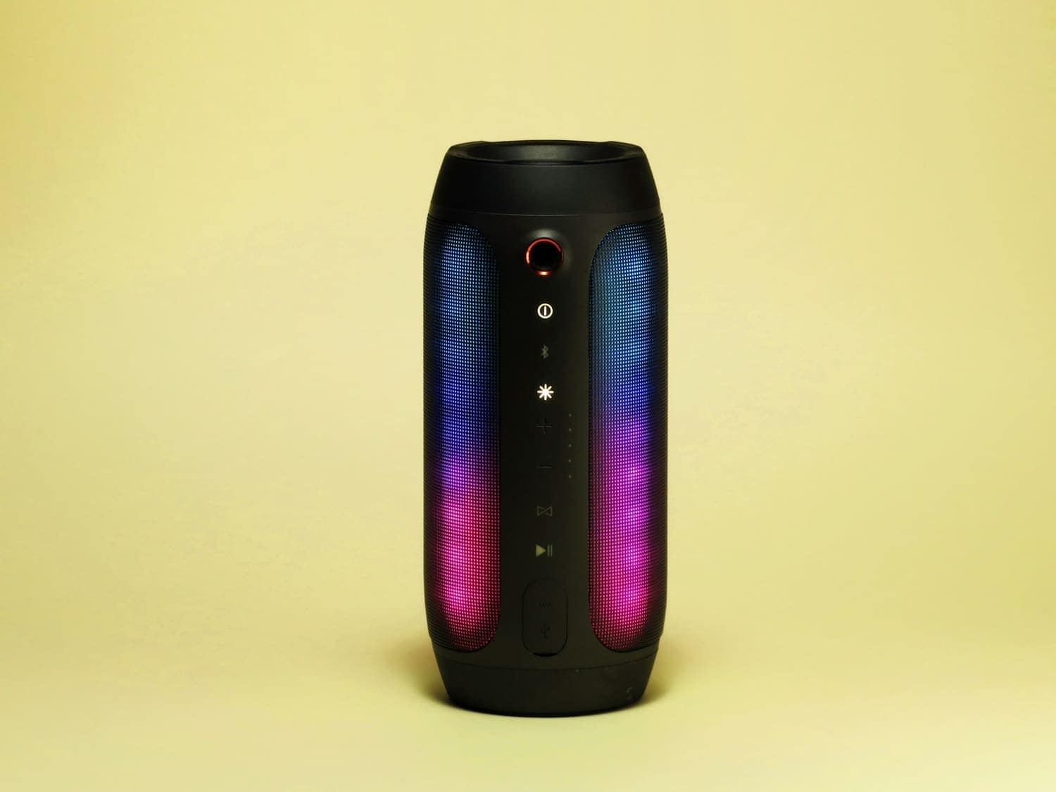 A portable speaker glowing on a pale yellow background