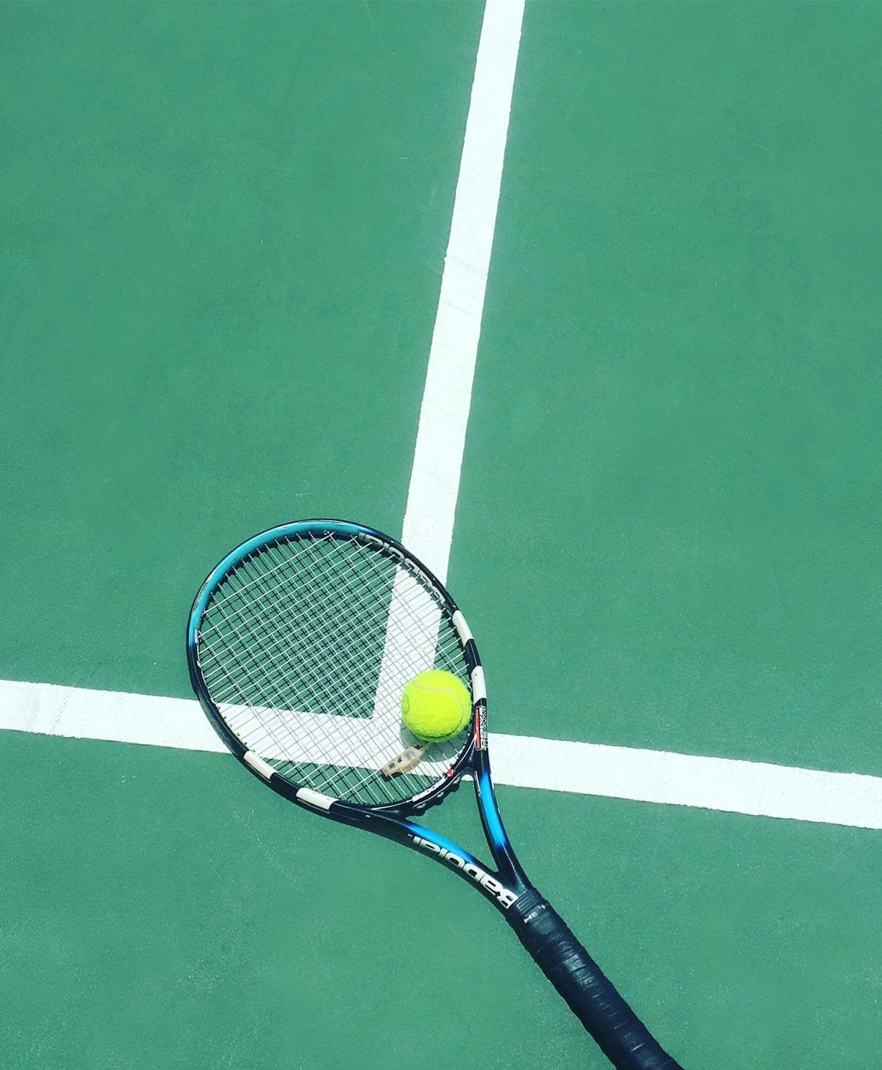 A tennis racket and ball on a green court
