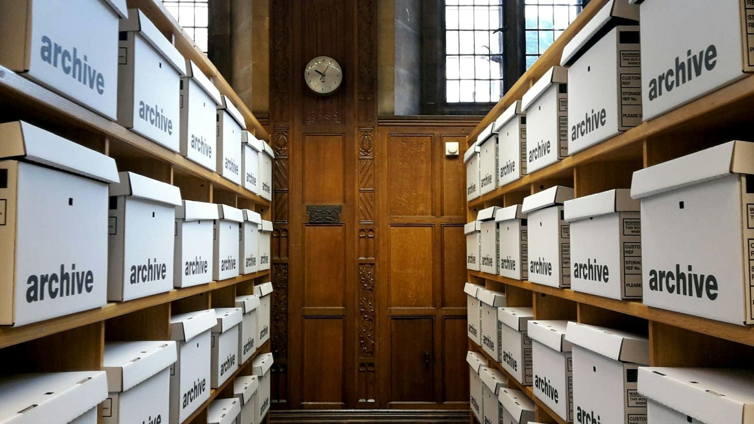 Rows of labelled archive boxes on wooden shelves