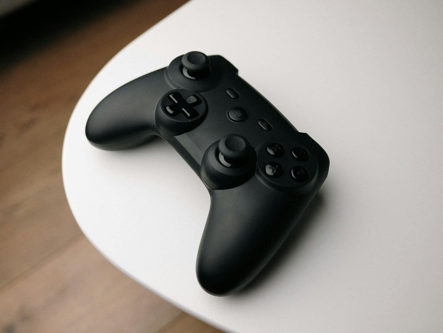 A black game controller on a white table