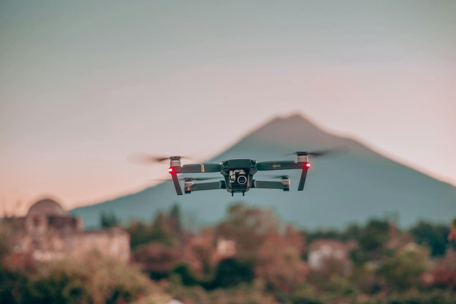 A drone hovering in front of a volcano at dusk