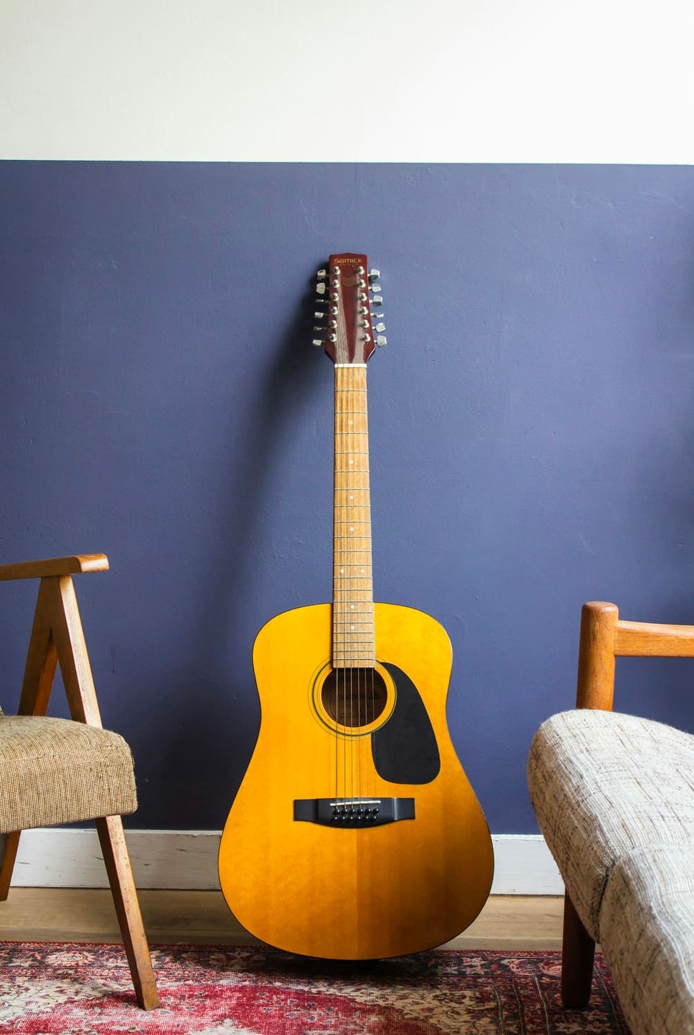Yellow acoustic guitar leaning against a blue wall