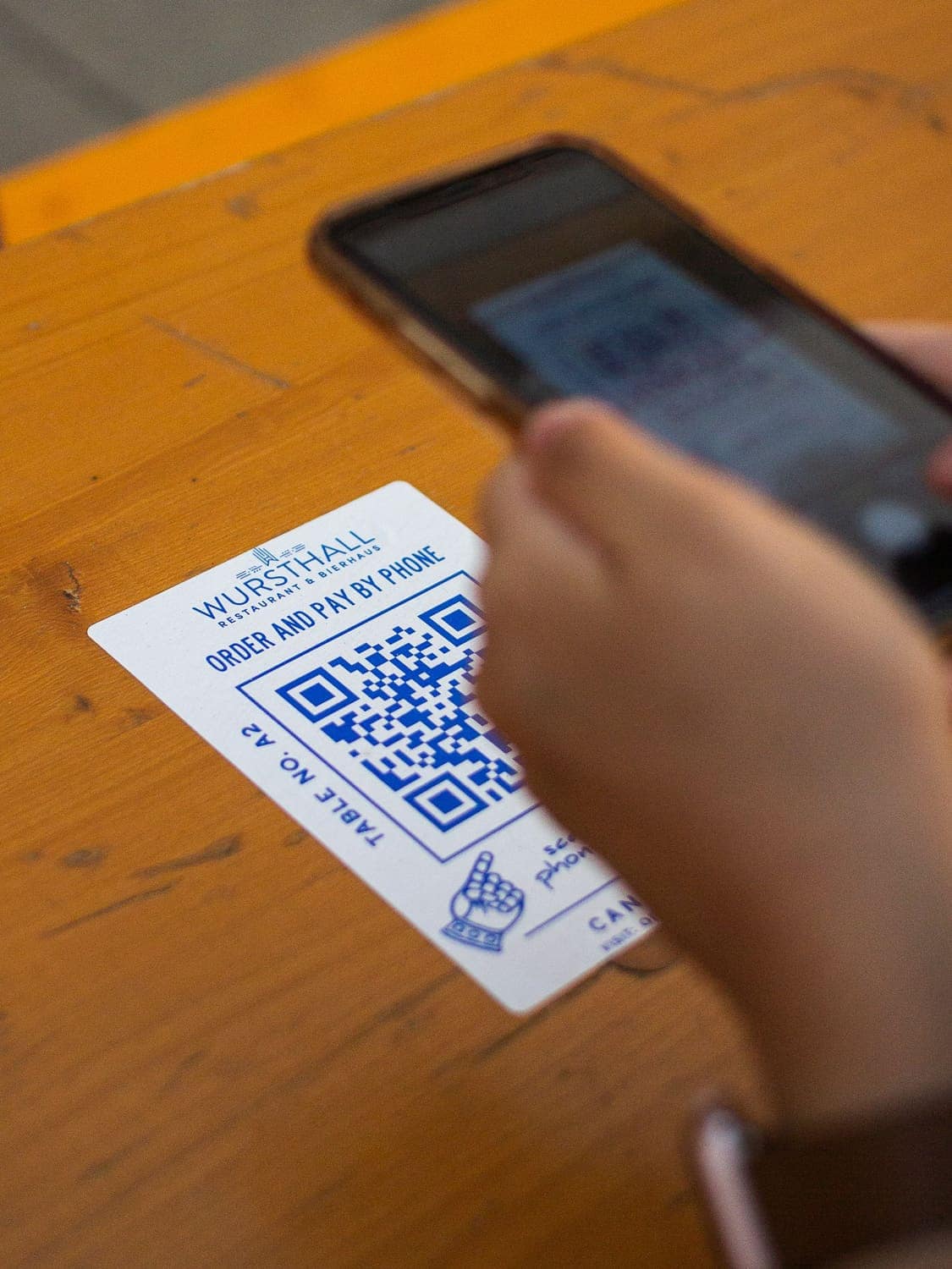 A phone scanning a printed QR code label on a wooden table