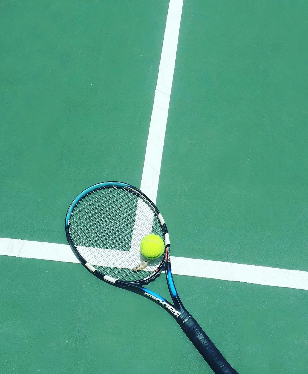 Tennis racket and ball on a green court