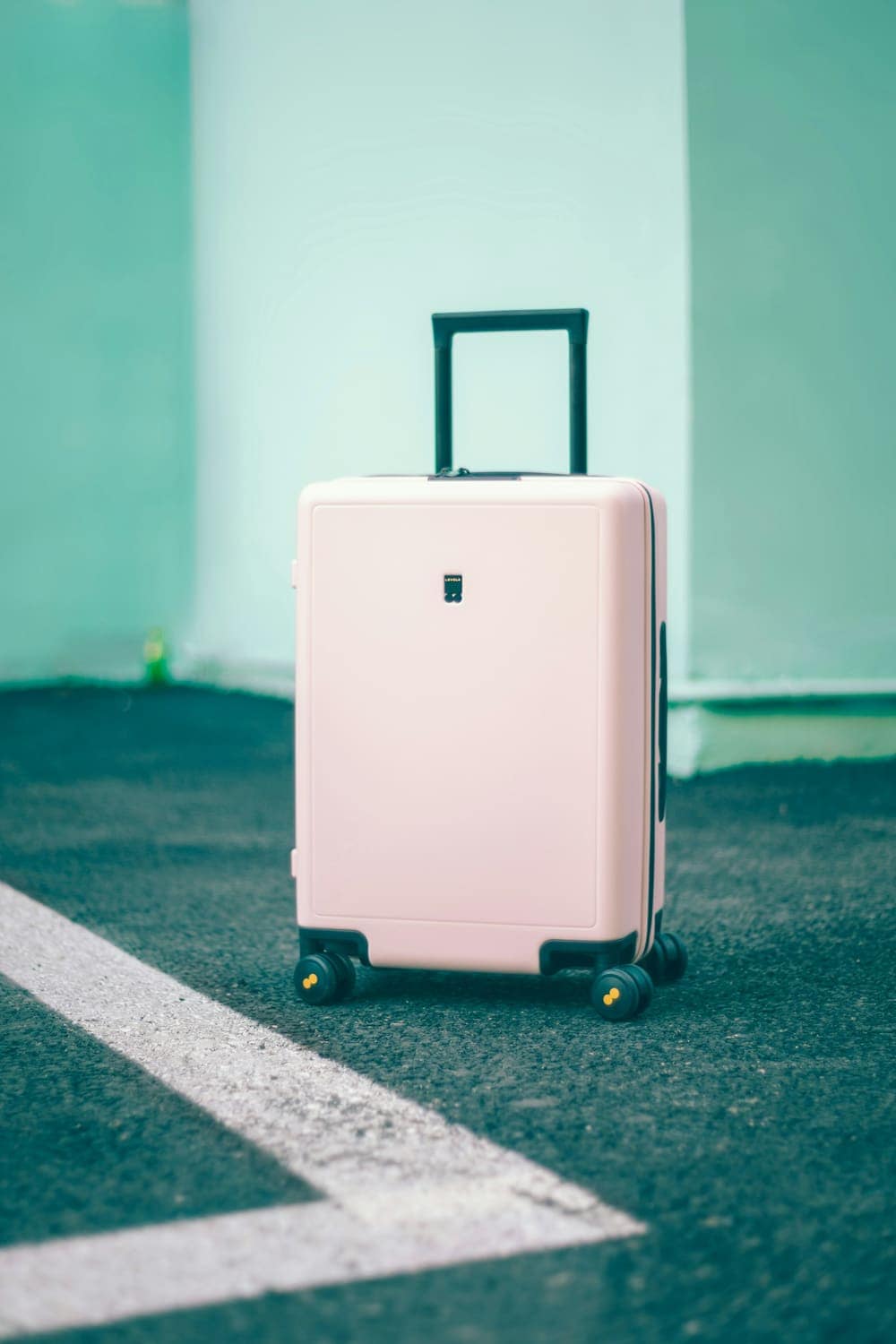 Pastel pink suitcase against a mint green wall