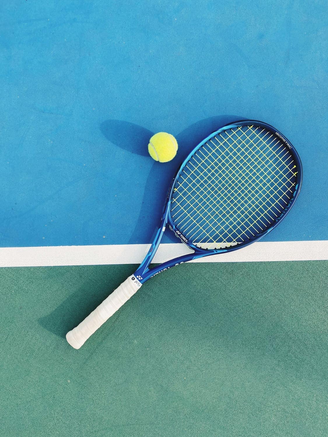 A blue and white tennis racket lying on a court
